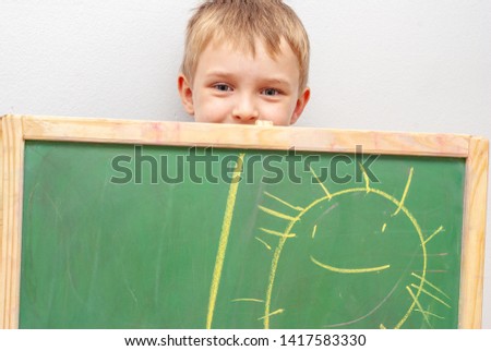 boy drawing sun with crayons on blackboard