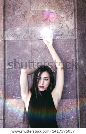 beautiful bright modern urban photo with light effects  of young brunette female fashion model outside on summer sunny day  with long hair and make up posing in front of old wall with copy space 