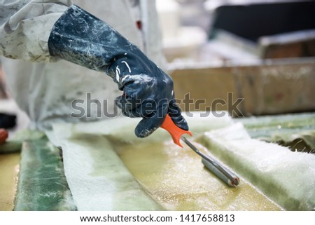 fiberglass factory worker rolls solution through fiberglass sheets Royalty-Free Stock Photo #1417658813