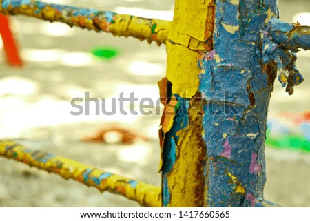 Old painted stairs in the playground close-up on a blurred background. peeling blue and yellow paint. many layers of paint on a metal pipe. terrible conditions of the playground.