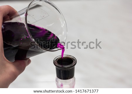 the transfusion of the substance purple, potassium permanganate, from a chemical glass into a bottle Royalty-Free Stock Photo #1417671377