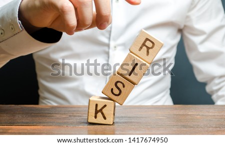 A businessman knocks down a tower of cubes with the word Risk. Risk management, cost assessment, business and investment safety. Strengthen business resilience and flexibility. Could not avoid failure Royalty-Free Stock Photo #1417674950