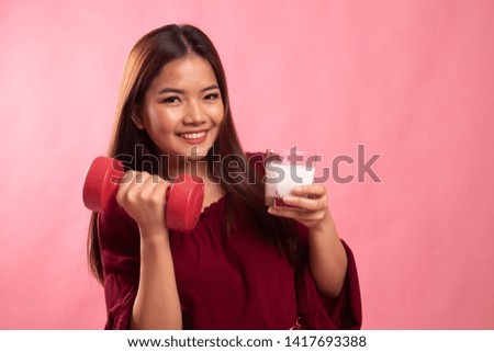 Healthy Asian woman drinking a glass of milk and dumbbell on pink background