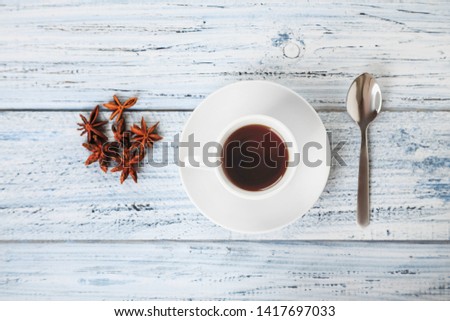 cup of coffee, spoon and dried Illicium anisatum or Japanese star anise on grey wooden table top view