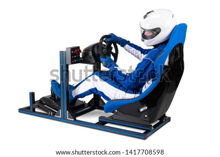race driver in blue overall with helmet taining on simracing aluminum simulator rig for video game racing. Motorsport car bucket seat steering wheel pedals isolated on white background