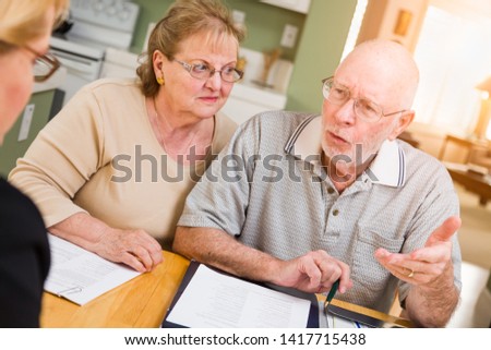 Senior Adult Couple Going Over Documents in Their Home with Agent At Signing.