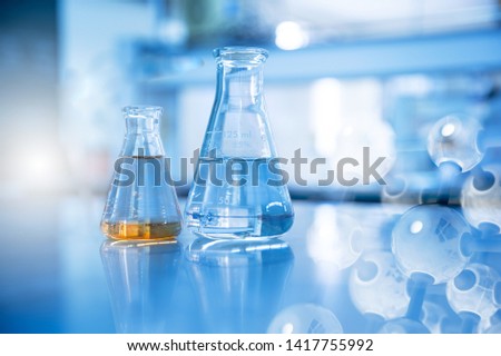 two glass flask in chemical science education laboratory with molecular structure in blue background Royalty-Free Stock Photo #1417755992