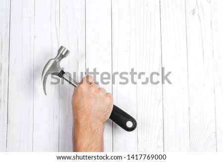 Tool. Hand is holding hammer isolated on a wooden background . 