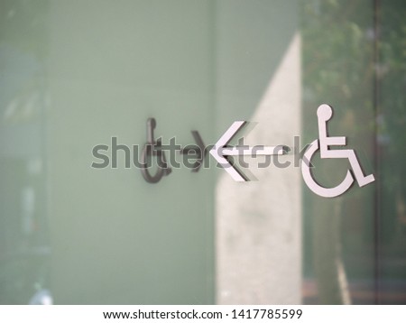 Wheelchair disabled logos with arrow showing path to entrance outside of a modern glass building