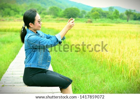 Women tourists sitting on a bamboo bridge photo shoot on the rice fields