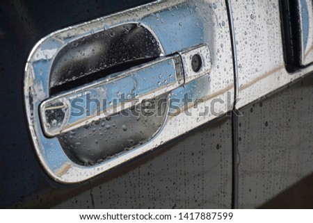 Raindrops on red car door handle, background. The texture of water on the car door handle. - image