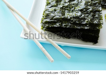 Dry korean organic seaweed and  chopsticks isolated on blue background. Crispy seaweed.Healthy food concept.top view, flat lay.
