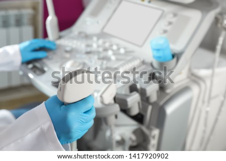 Sonographer holding ultrasound machine probe in clinic, closeup with space for text Royalty-Free Stock Photo #1417920902