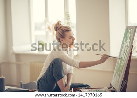 fair-haired female freelancer working at home. close up side view photo.windows with flowers in the background of the photo
