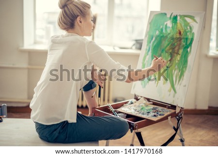 girl drawing with green color. back view photo. The development of painting