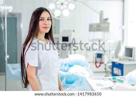 attarctive female surgeon with long black hair posing with her uniform in the operation room. close up photo. copy space . job, occupation