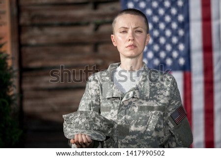 Beautiful american soldier in uniform standing in front of american flag