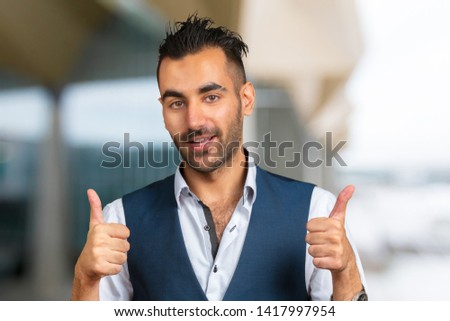 Closeup portrait of handsome young smiling man giving  thumbs up