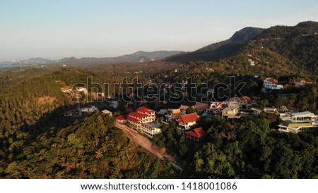 Luxury villas on mountain slope. Drone view of houses located amidst exotic trees on green mountains on sunny day on tropical island