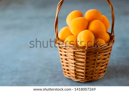 Ripe apricots to a brown basket on a gray background. Soft focus