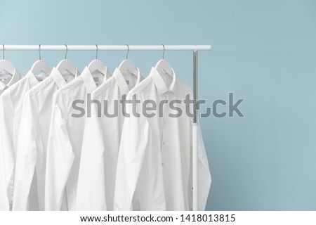 Rack with clothes after dry-cleaning on light background Royalty-Free Stock Photo #1418013815