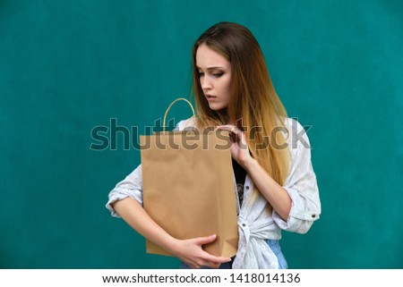 Photograph of a portrait of a beautiful girl woman with long dark flowing hair, loves shopping, on a green background with packages. She is standing in different poses and smiling. Made in studio