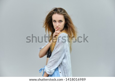 Photograph of a portrait of a beautiful girl woman with long dark flowing hair, satisfied life on a gray background. She stands in front of the camera in different poses with different emotions.