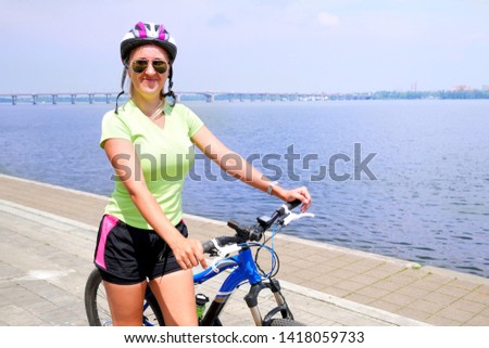 beautiful athletic girl in helmet and sunglasses with bike is smiling in sunny summer day, healthy life concept, girl and bicycle 