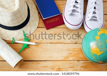 passports, travel map, summer hat,  globe, white sneakers and toy aircraft on wooden background with copy space,  travel concept