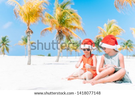 Adorable kids in Santa hats celebrating Christmas on the beach