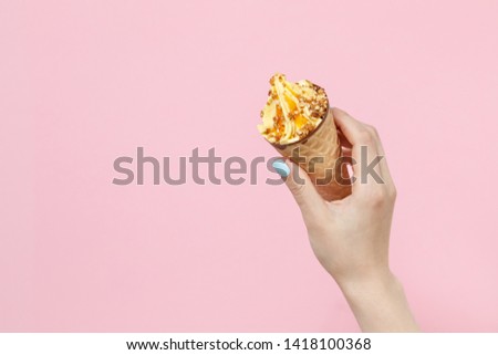 Woman holding Ice Cream in a waffles cone on color background.