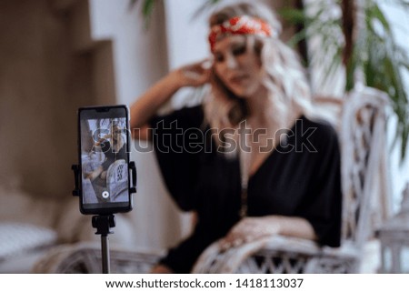 Young pretty women takes pictures of himself remotely, using selfie stick, poses in studio. Moroccan Studio Room