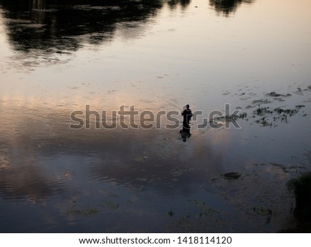 man fishing on the river at sunset