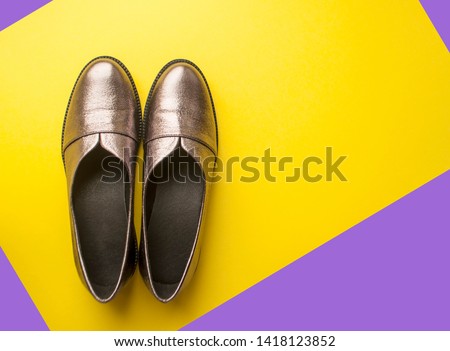 Pair of sparkly female shoes on yellow and purple background with copyspace.