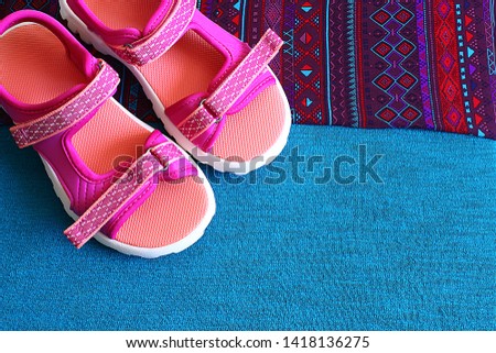Summer pink children's sandals on a free pink and turquoise background, a place for an inscription on the background near the beach sandals bright shoes

