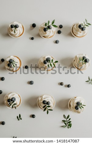 Tasty cupcakes with whipped vanilla cream and berries on white wooden table. Picture for a menu or a confectionery catalog. Top view.