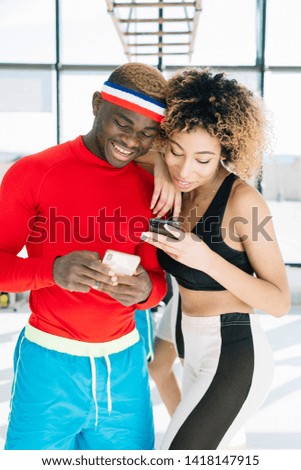 two friends using social media on the phone while they are doing workout.
