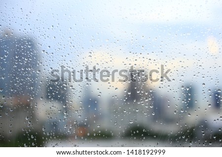 office window covered with rain water. water spray on window. after rain traffic, worker stuck in the office concepts. blur urban skyline background. rainy season concepts.