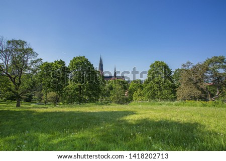 Beautiful view of green city landscape with top of famous cathedral towers on blue sky background. Europe. Sweden. Uppsala.