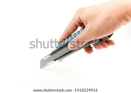man's hand is holding a construction knife cutter on a white background with copy space. cutting by knife on white background Royalty-Free Stock Photo #1418224916