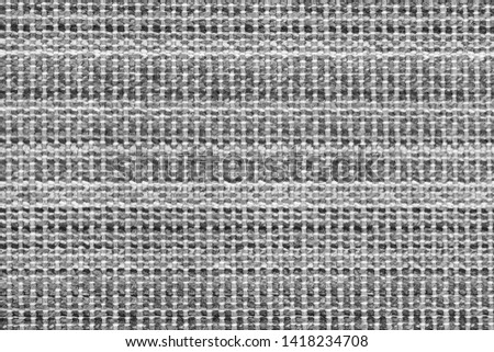 White and black knitted fabric background texture. gray fabric with a pattern. Fragment grey wool carpet, bright wicker dark rug