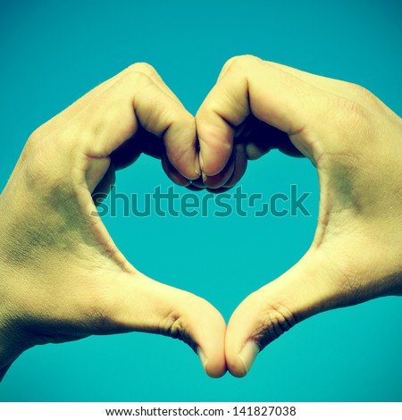 picture of man hands forming a heart over the blue sky, with a retro effect