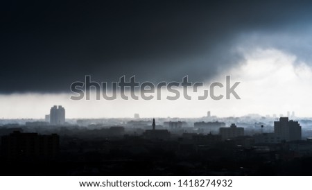 Silhouette of misty city and gloomy atmosphere under dark black clouds during a storm in Bangkok Thailand.