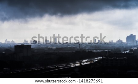 Silhouette of misty city and gloomy atmosphere under dark black clouds during a storm in Bangkok Thailand.