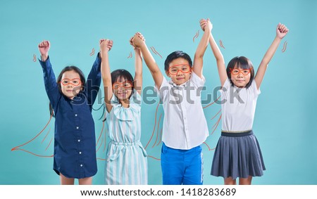 Group of happy smiling asian heroes children hands up isolated on light blue background .