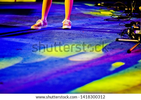 The singer's legs stand on the stage with a light on the stage