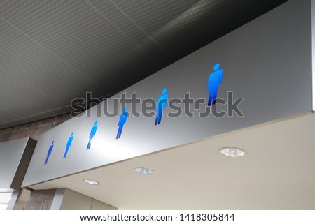 A blue glowing sign signifying a men’s bathroom or lavatory entrance.