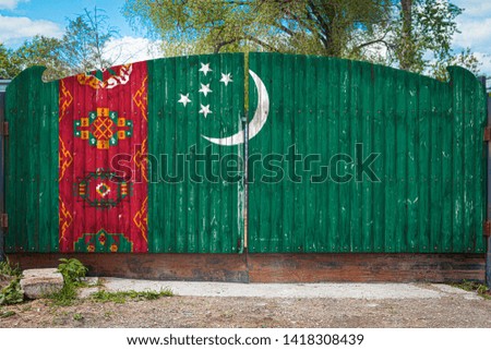 Close-up of the national flag of Turkmenistan on a wooden gate at the entrance to the closed territory on a summer day. The concept of storage of goods, entry to a closed area, tourism in Turkmenistan