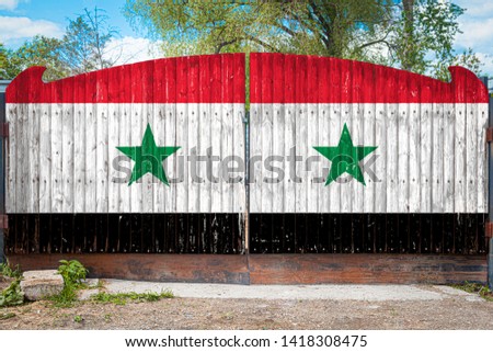Close-up of the national flag of Syria on a wooden gate at the entrance to the closed territory on a summer day. The concept of storage of goods, entry to a closed area, tourism in Syria