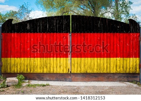 Close-up of the national flag of Germany  on a wooden gate at the entrance to the closed territory on a summer day. The concept of storage of goods, entry to a closed area, tourism in Germany 